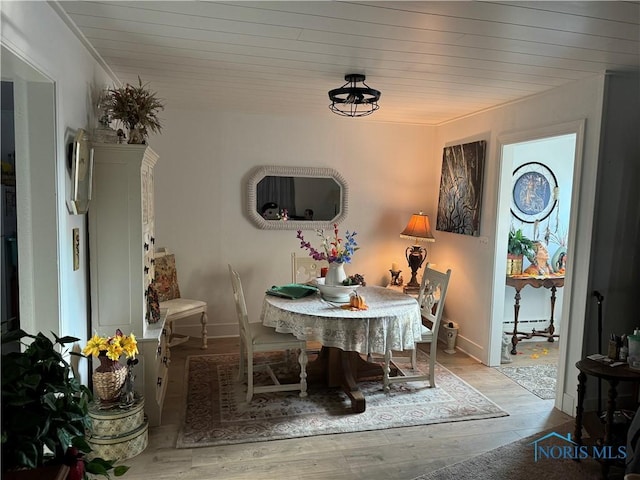 dining room featuring light hardwood / wood-style floors, a baseboard heating unit, and wood ceiling