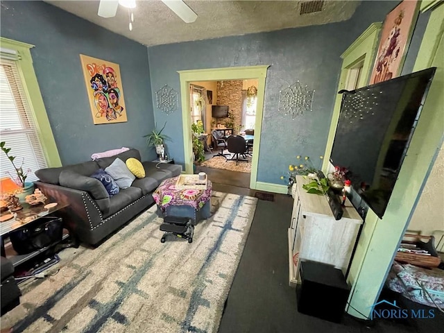 living room with ceiling fan and a textured ceiling