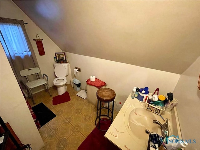 bathroom with toilet, tile patterned floors, vanity, and vaulted ceiling