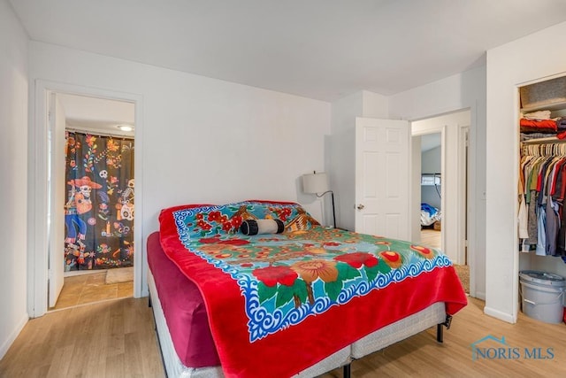 bedroom featuring a spacious closet, light wood-type flooring, connected bathroom, and a closet