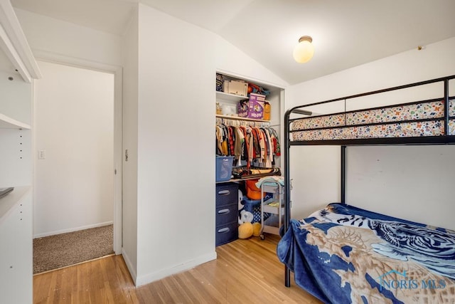 bedroom with a closet, wood-type flooring, and lofted ceiling