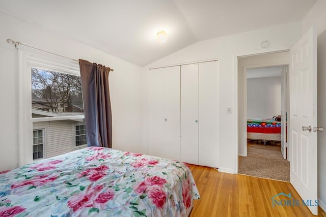 bedroom with a closet, light hardwood / wood-style floors, and lofted ceiling