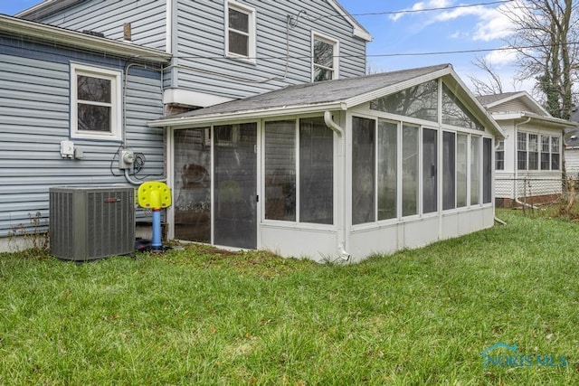 rear view of property featuring a lawn, a sunroom, and central AC unit