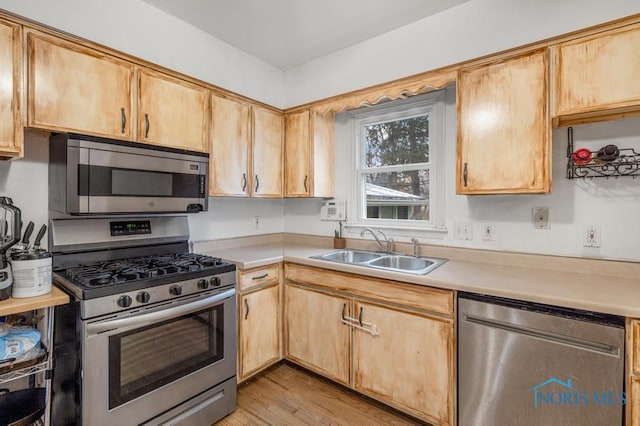 kitchen with appliances with stainless steel finishes, light wood-type flooring, light brown cabinets, and sink