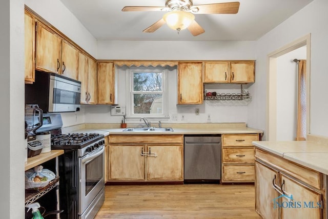 kitchen featuring stainless steel appliances, ceiling fan, light hardwood / wood-style floors, and sink