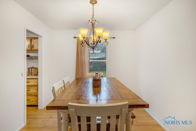 dining room with light hardwood / wood-style floors and a chandelier