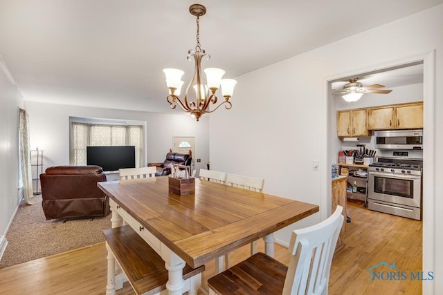 dining area featuring light hardwood / wood-style flooring and ceiling fan with notable chandelier