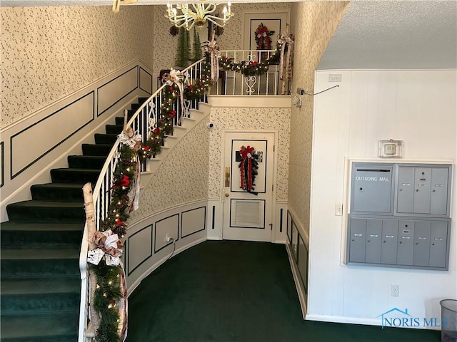 staircase featuring carpet, a mail area, and a textured ceiling