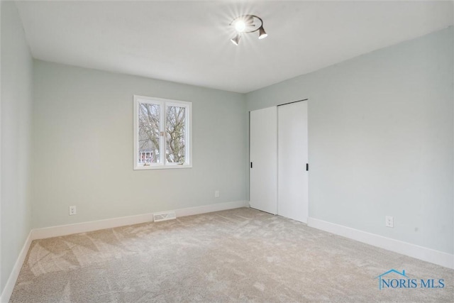 unfurnished bedroom with light carpet and a closet