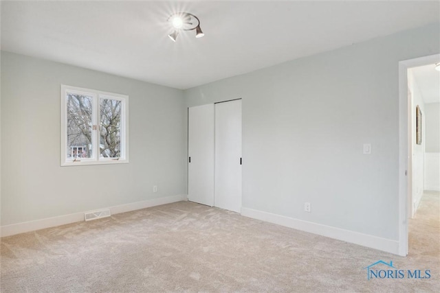 unfurnished bedroom with light carpet and a closet