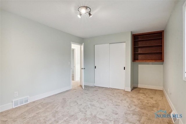 unfurnished bedroom featuring a closet and light colored carpet