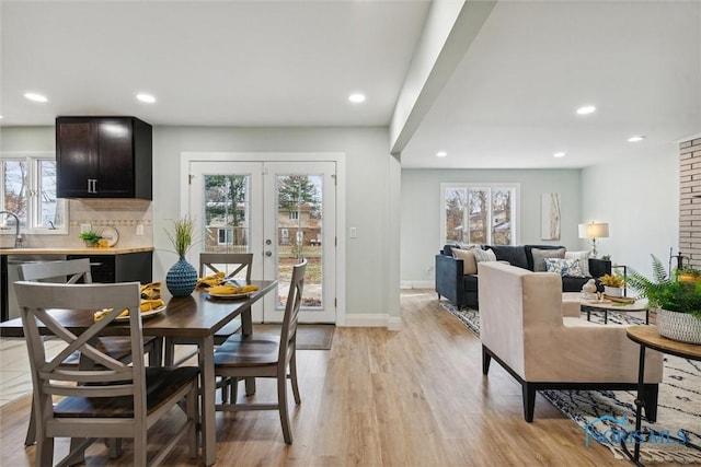 dining area featuring french doors, light wood-type flooring, and a healthy amount of sunlight