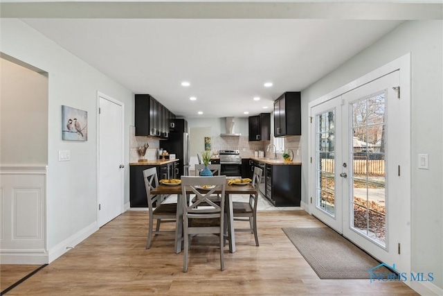 dining space featuring sink, light hardwood / wood-style flooring, and french doors