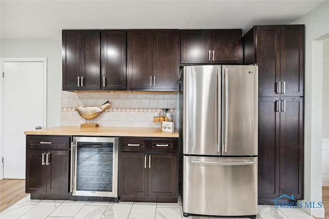 kitchen with stainless steel fridge, dark brown cabinets, beverage cooler, and wood counters