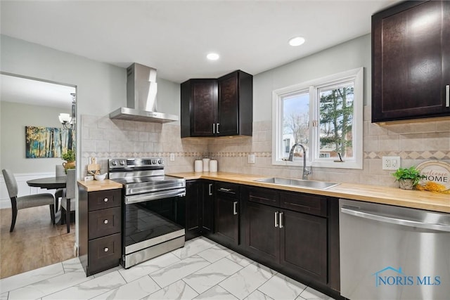 kitchen featuring wooden counters, sink, wall chimney exhaust hood, appliances with stainless steel finishes, and dark brown cabinetry