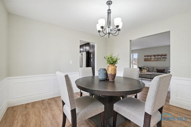 dining room with light wood-type flooring and a notable chandelier