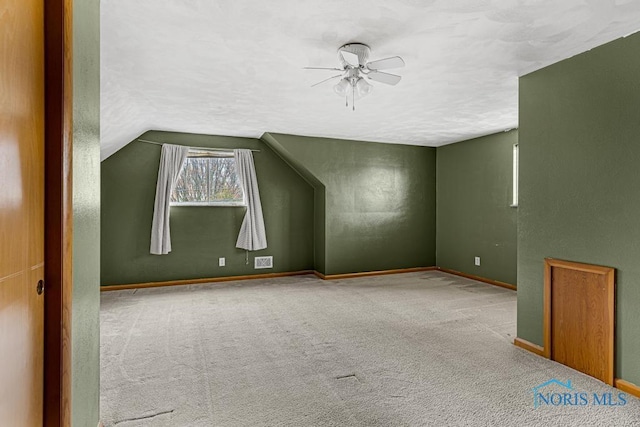 bonus room with a textured ceiling, light colored carpet, vaulted ceiling, and ceiling fan