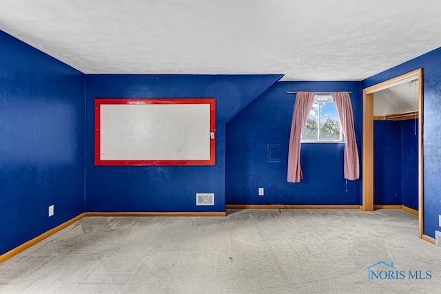 spare room featuring carpet flooring and lofted ceiling