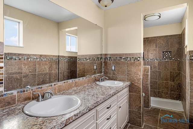 bathroom featuring a tile shower, vanity, and tile walls