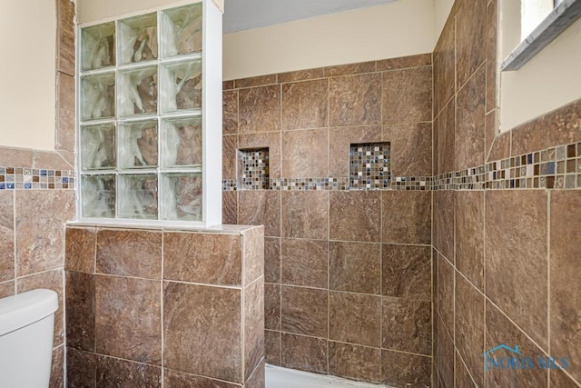 bathroom with tiled shower, tile walls, and toilet