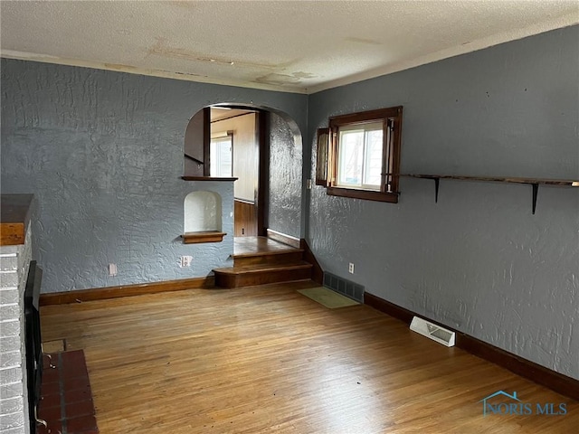 unfurnished living room with hardwood / wood-style flooring, a fireplace, and a textured ceiling