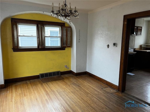 spare room featuring crown molding, a chandelier, and hardwood / wood-style flooring