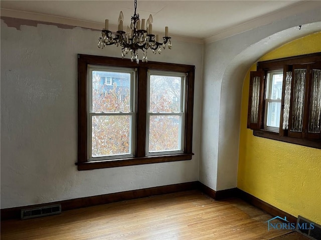 unfurnished dining area featuring a chandelier, light hardwood / wood-style flooring, a healthy amount of sunlight, and ornamental molding