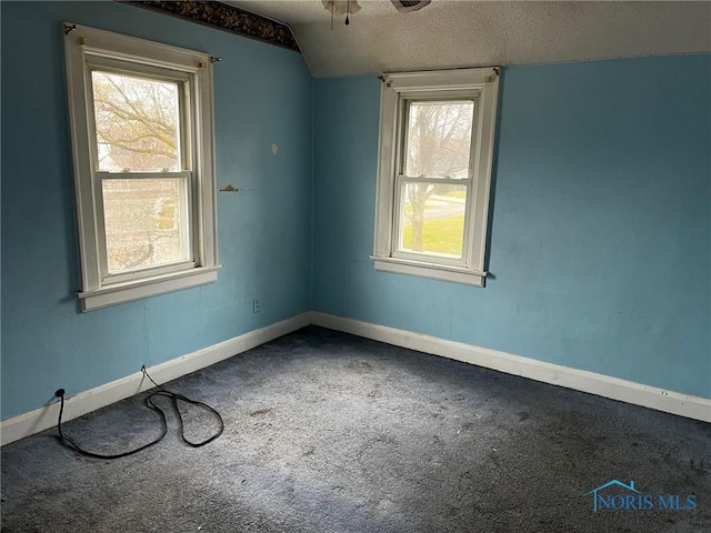 carpeted empty room featuring a textured ceiling, ceiling fan, and lofted ceiling