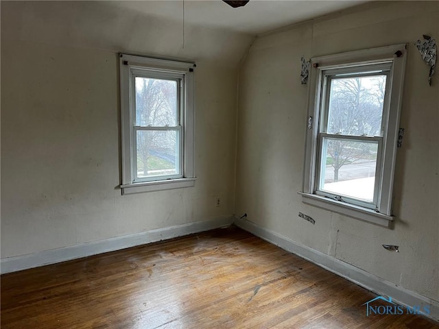 spare room featuring hardwood / wood-style flooring and lofted ceiling