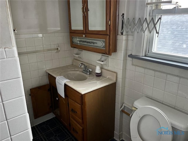 bathroom featuring tile patterned floors, vanity, tile walls, and toilet