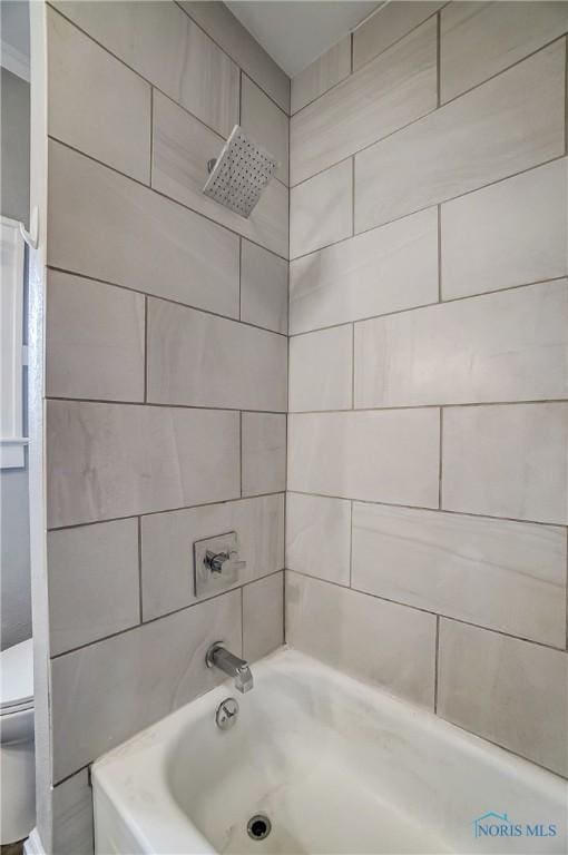 bathroom featuring tiled shower / bath combo and toilet