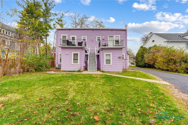 view of front of house with a balcony and a front lawn