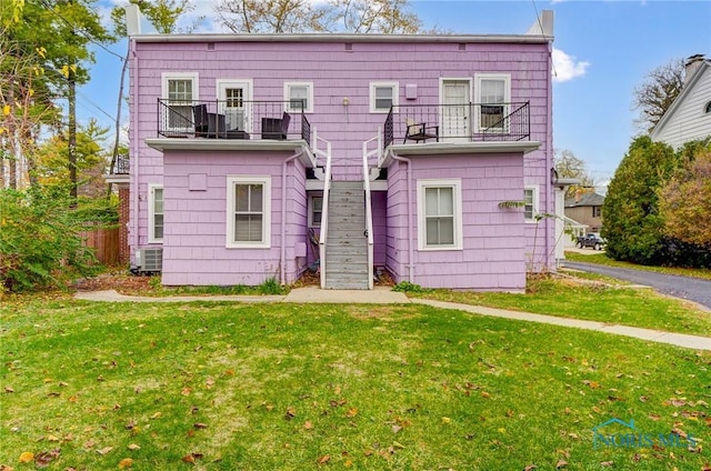 back of house with a balcony and a yard