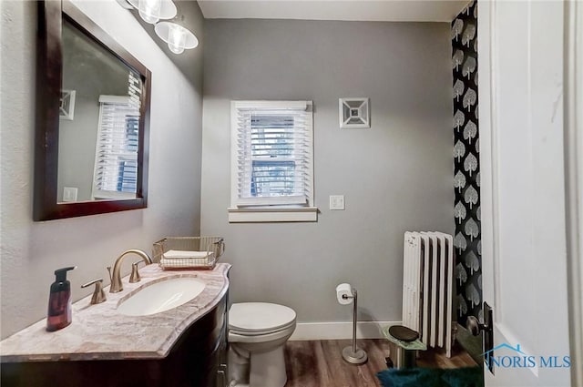 bathroom with radiator, vanity, wood-type flooring, and toilet