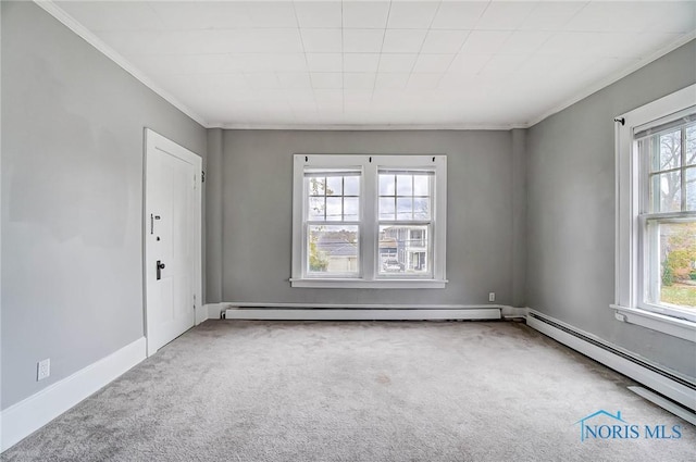 empty room featuring a healthy amount of sunlight, carpet floors, crown molding, and a baseboard heating unit