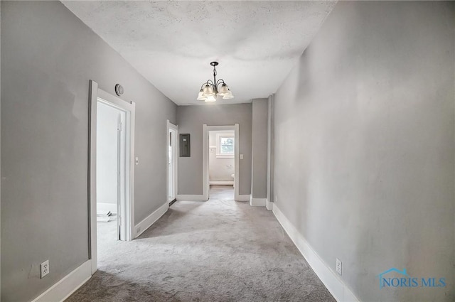 corridor with light colored carpet, a textured ceiling, electric panel, and an inviting chandelier