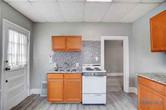 kitchen with decorative backsplash, light hardwood / wood-style floors, white range oven, and sink