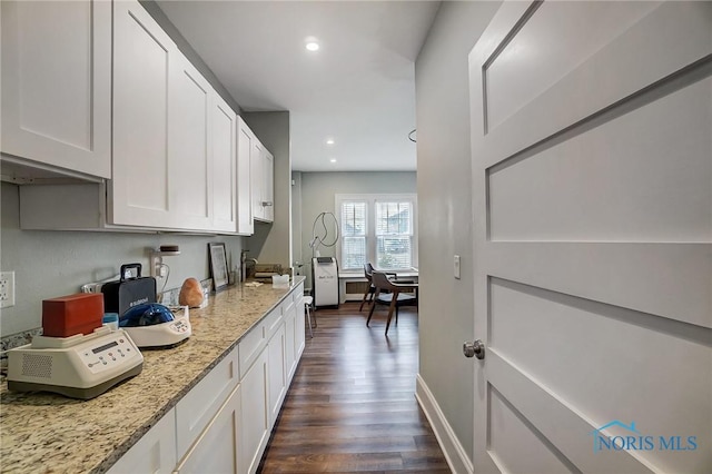 kitchen with dark hardwood / wood-style flooring, white cabinetry, and light stone counters