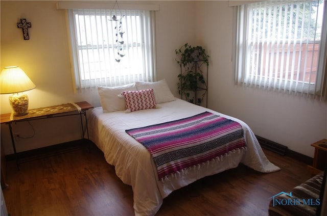 bedroom with multiple windows and dark hardwood / wood-style floors