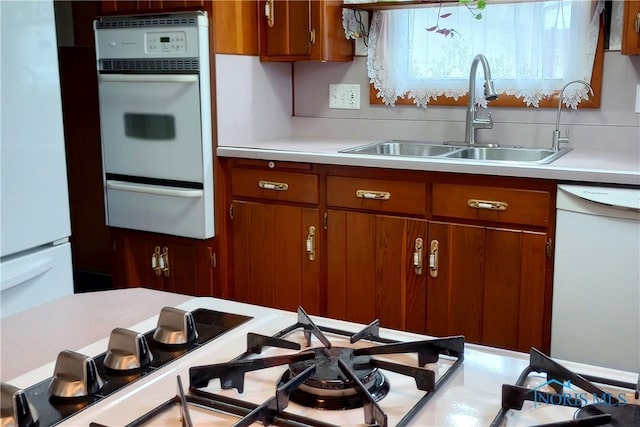 kitchen featuring backsplash, white appliances, and sink