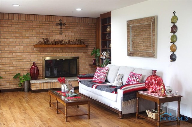 living room featuring a fireplace, wood-type flooring, and brick wall