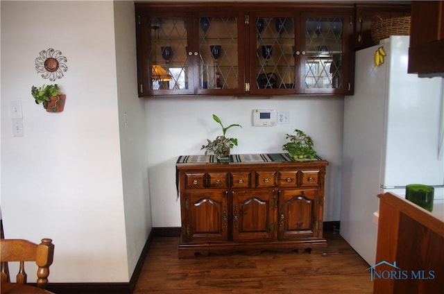 bar with dark hardwood / wood-style flooring, dark brown cabinets, and white refrigerator