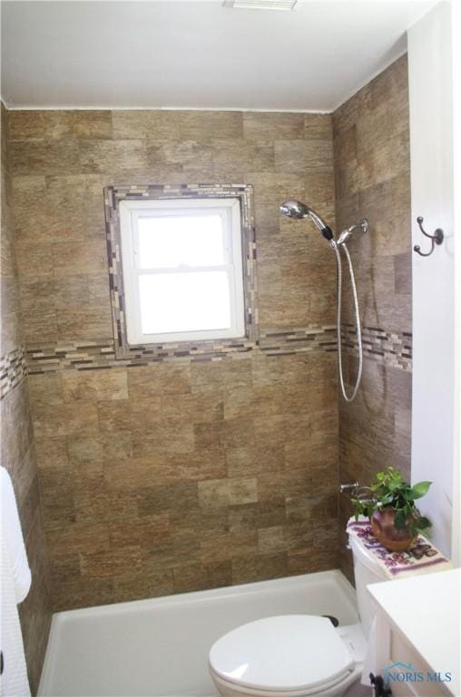 bathroom featuring a tile shower, vanity, and toilet