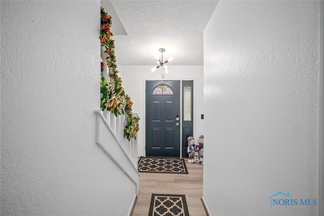 foyer with a textured ceiling, light hardwood / wood-style flooring, and a notable chandelier