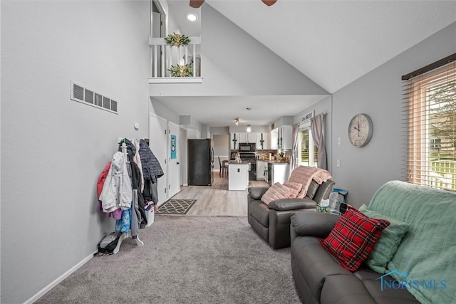 living room with light carpet, high vaulted ceiling, a healthy amount of sunlight, and ceiling fan