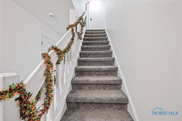 stairs featuring carpet flooring and a textured ceiling