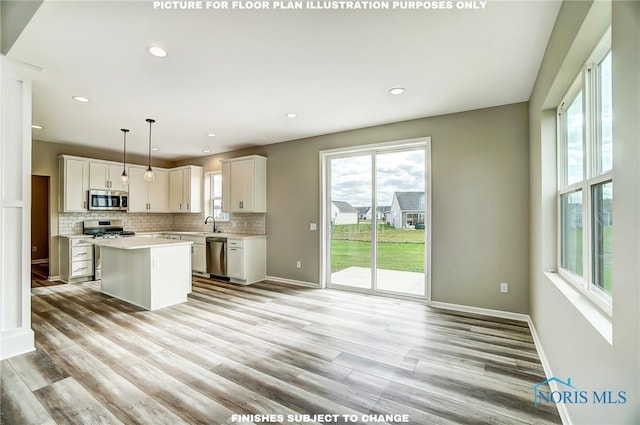 kitchen with white cabinets, a kitchen island, decorative light fixtures, and appliances with stainless steel finishes