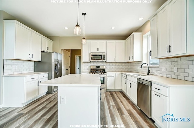 kitchen featuring appliances with stainless steel finishes, a kitchen island, sink, pendant lighting, and white cabinetry