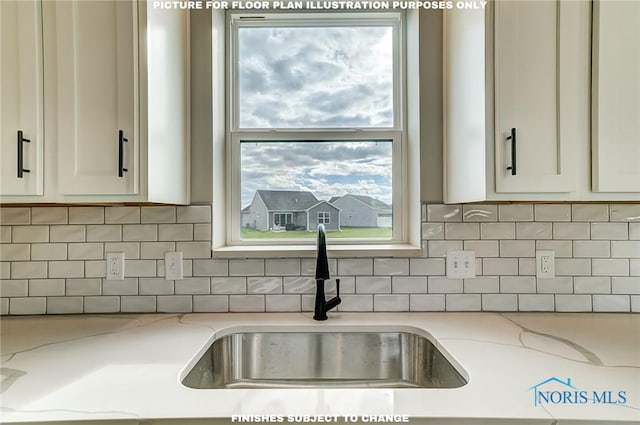 details featuring decorative backsplash, light stone counters, and sink