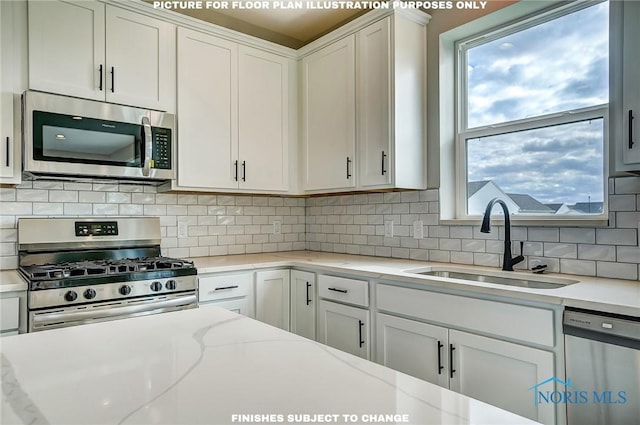 kitchen with sink, light stone counters, decorative backsplash, white cabinets, and appliances with stainless steel finishes